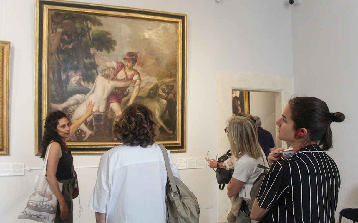 Tour guide explaining a painting to visitors inside Palazzo Barberini, Rome.
