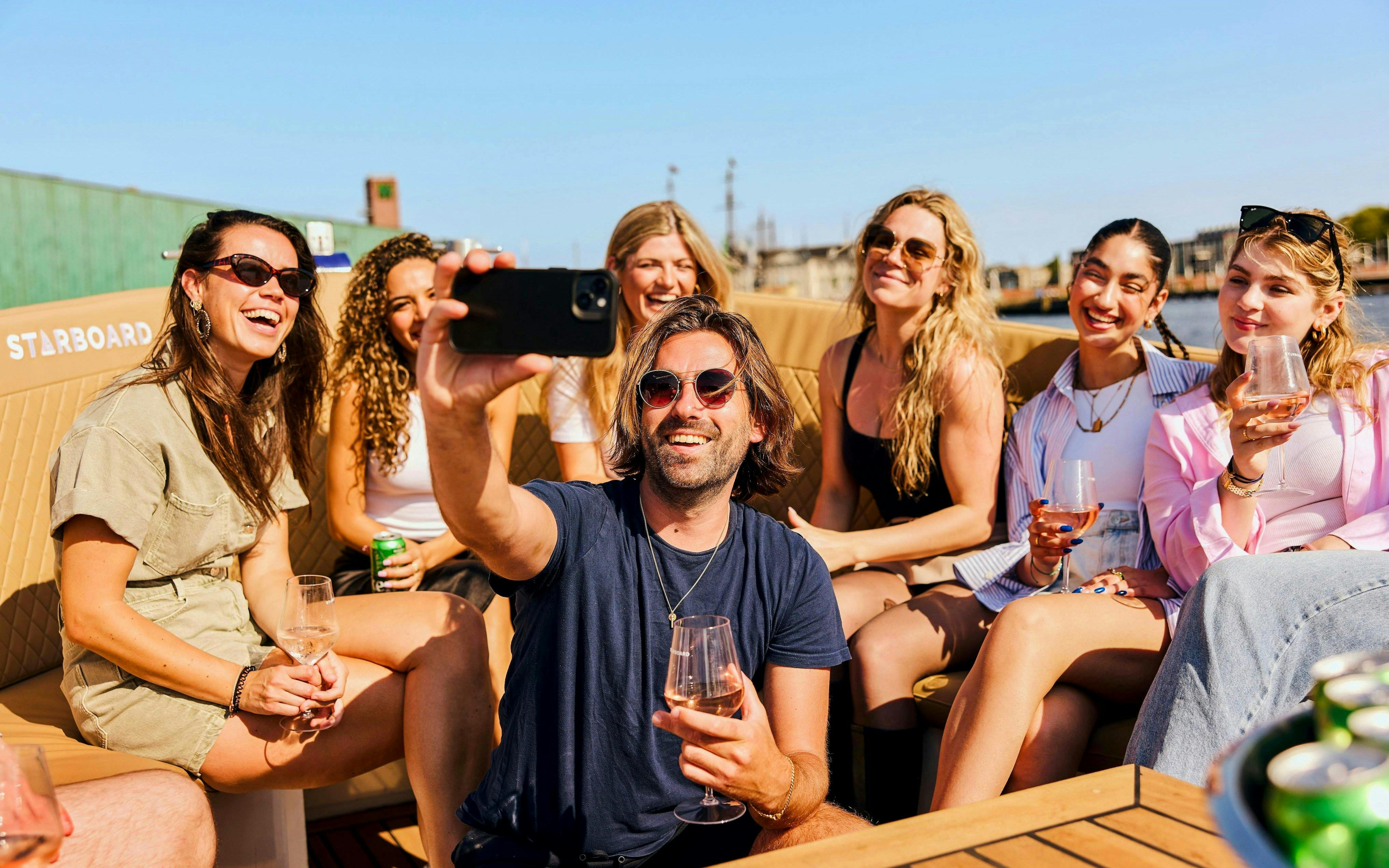 Guests enjoying drinks on a canal booze cruise in Amsterdam.