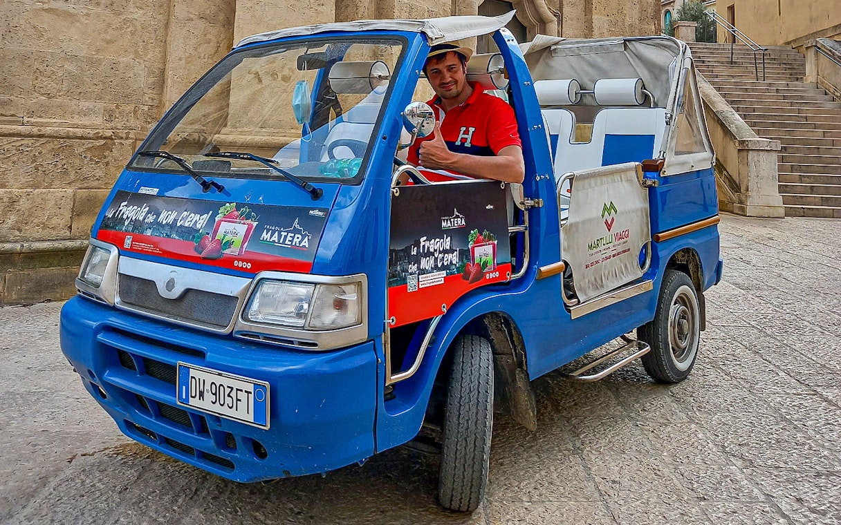 Tour guide in a blue vehicle for 45-min Sassi of Matera tour with audio guide.
