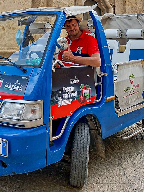 Tour guide in a blue vehicle for 45-min Sassi of Matera tour with audio guide.