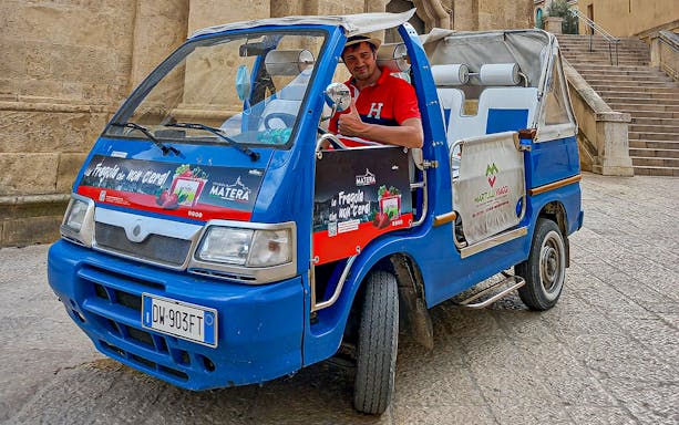 Tour guide in a blue vehicle for 45-min Sassi of Matera tour with audio guide.