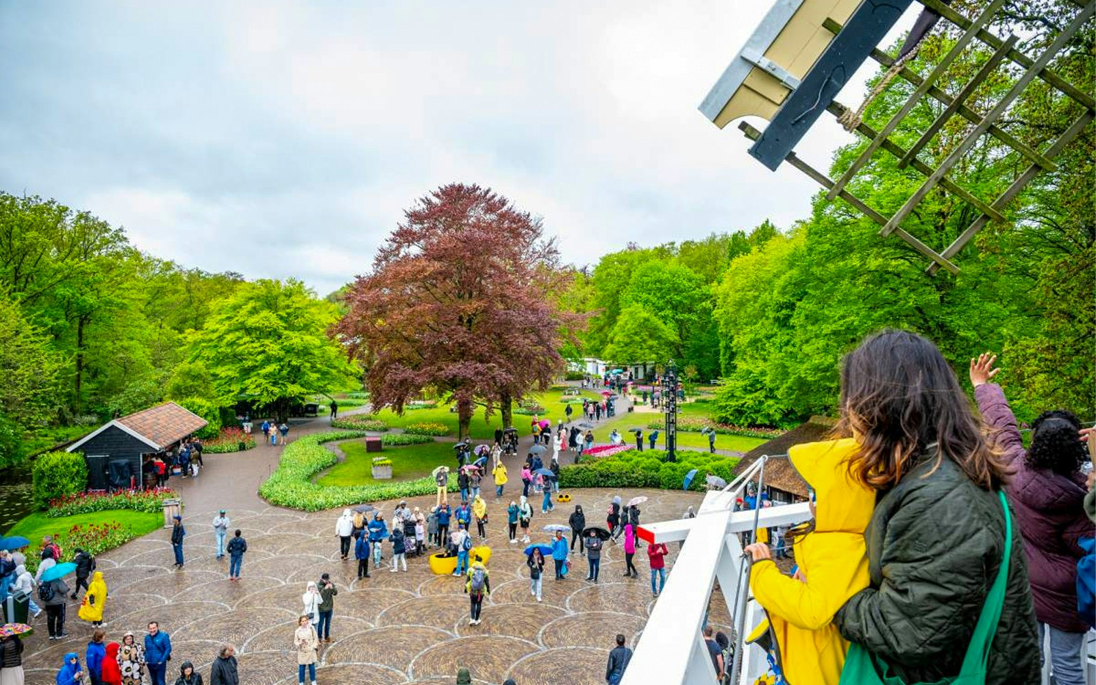 Visitors enjoying the view from Keukenhof windmill, surrounded by gardens and pathways.