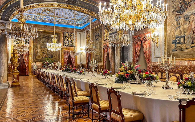 Dining room with chandeliers and ornate decor inside Royal Palace of Madrid.