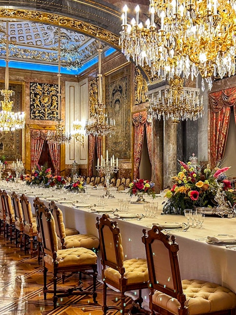 Dining room with chandeliers and ornate decor inside Royal Palace of Madrid.