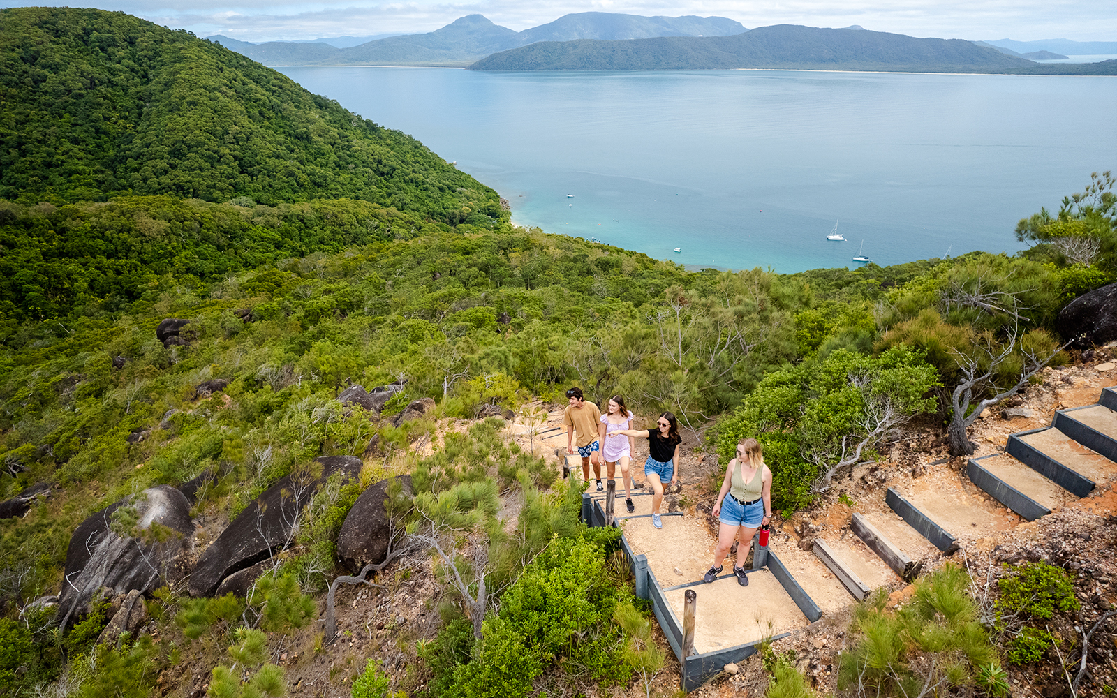 Hikers ascending a trail with views of Fitzroy and Green Islands in the background.