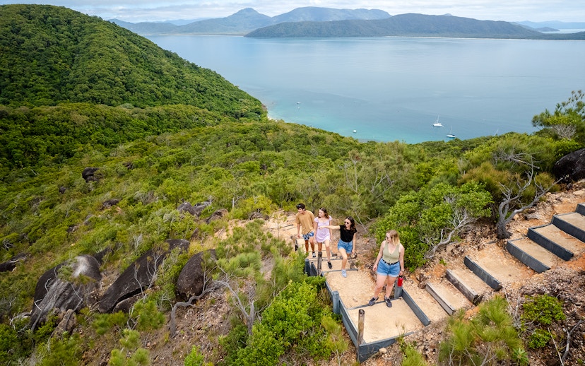 Hikers ascending a trail with views of Fitzroy and Green Islands in the background.