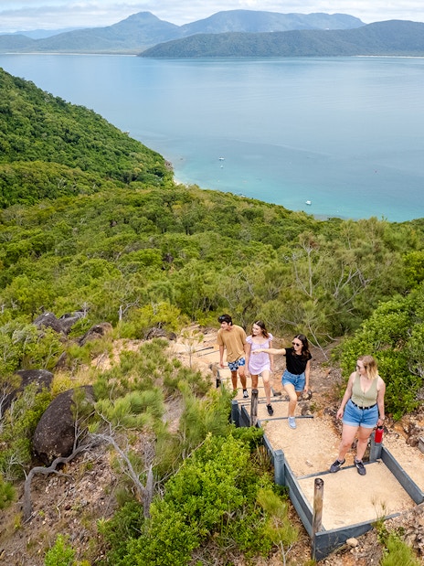 Hikers ascending a trail with views of Fitzroy and Green Islands in the background.