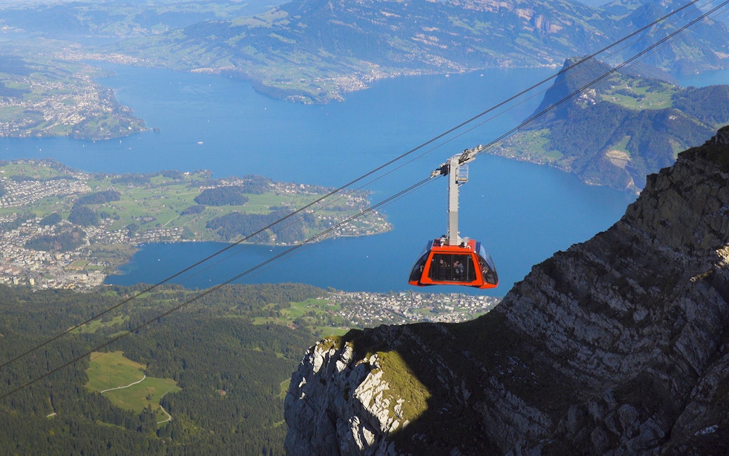 Cable car ascending above Lucerne Lake with scenic mountain and lake views.