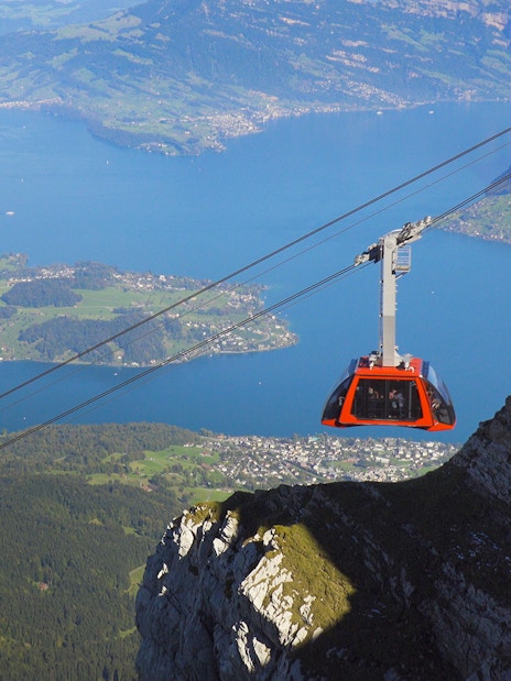Cable car ascending above Lucerne Lake with scenic mountain and lake views.