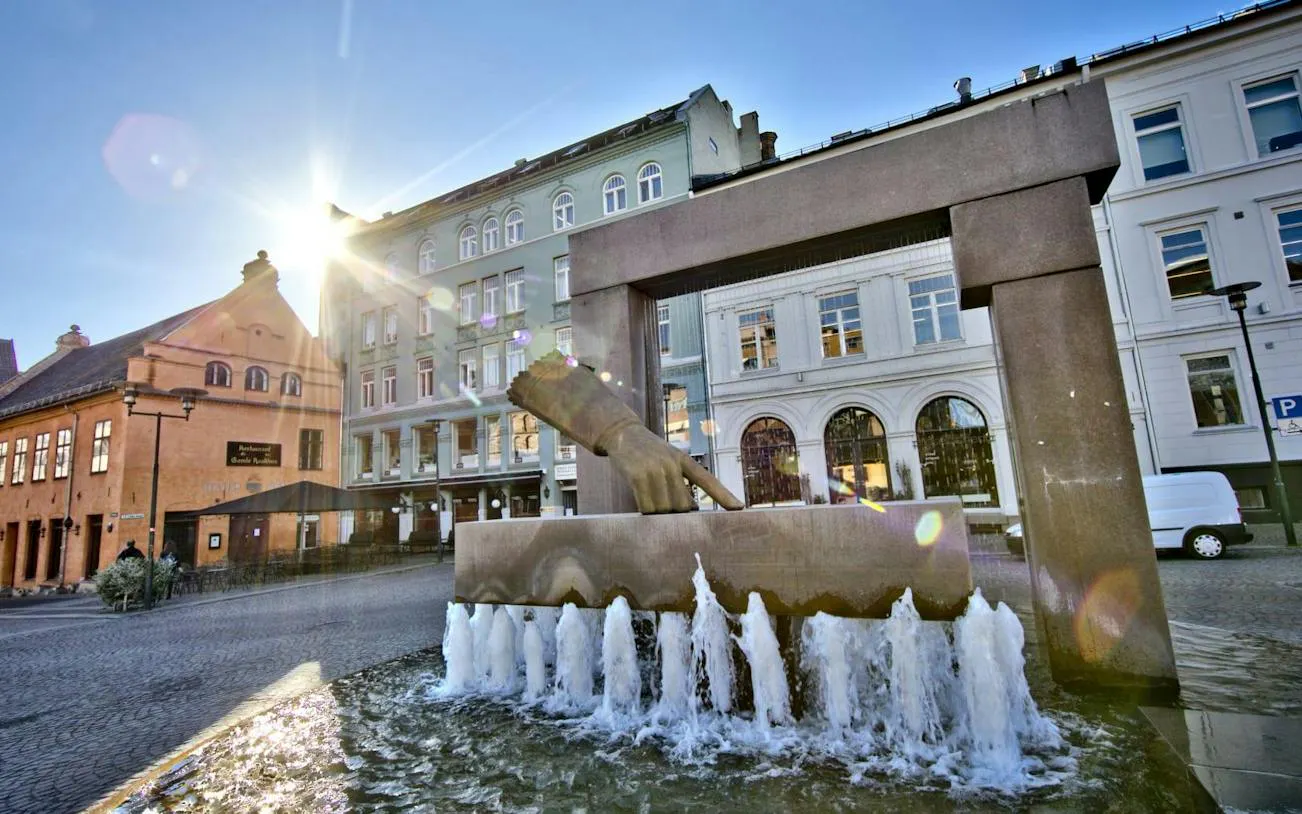 Fountain with pointing hand sculpture in central Oslo during walking tour.