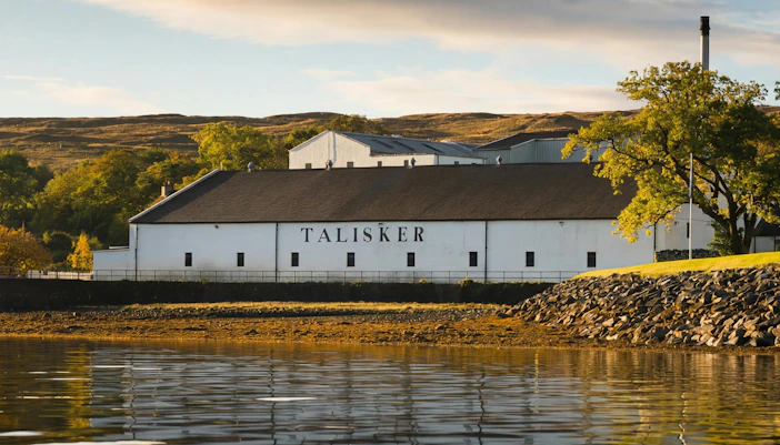 Talisker Distillery on the Isle of Skye, Scotland, with surrounding landscape and water.