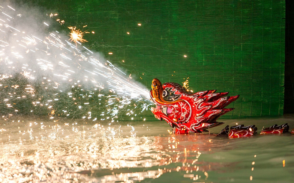 Dragon puppet emitting sparks during Golden Water Puppet Show in Vietnam.