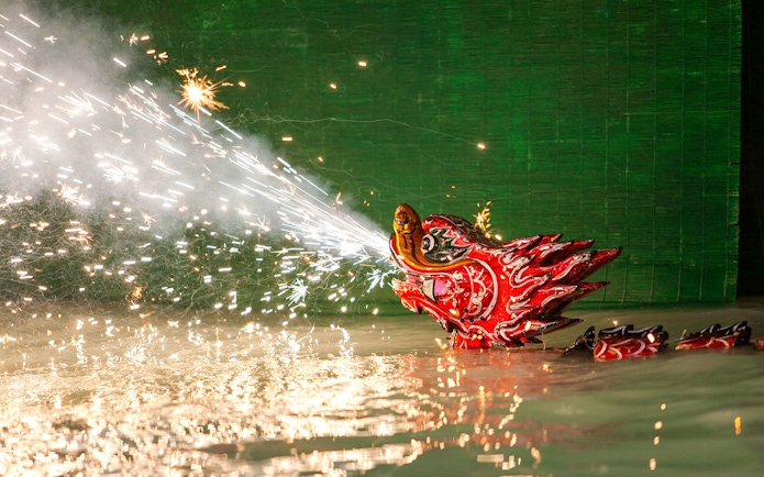 Dragon puppet emitting sparks during Golden Water Puppet Show in Vietnam.