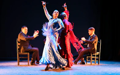 Flamenco dancers performing at Teatro Flamenco Sevilla with musicians clapping.