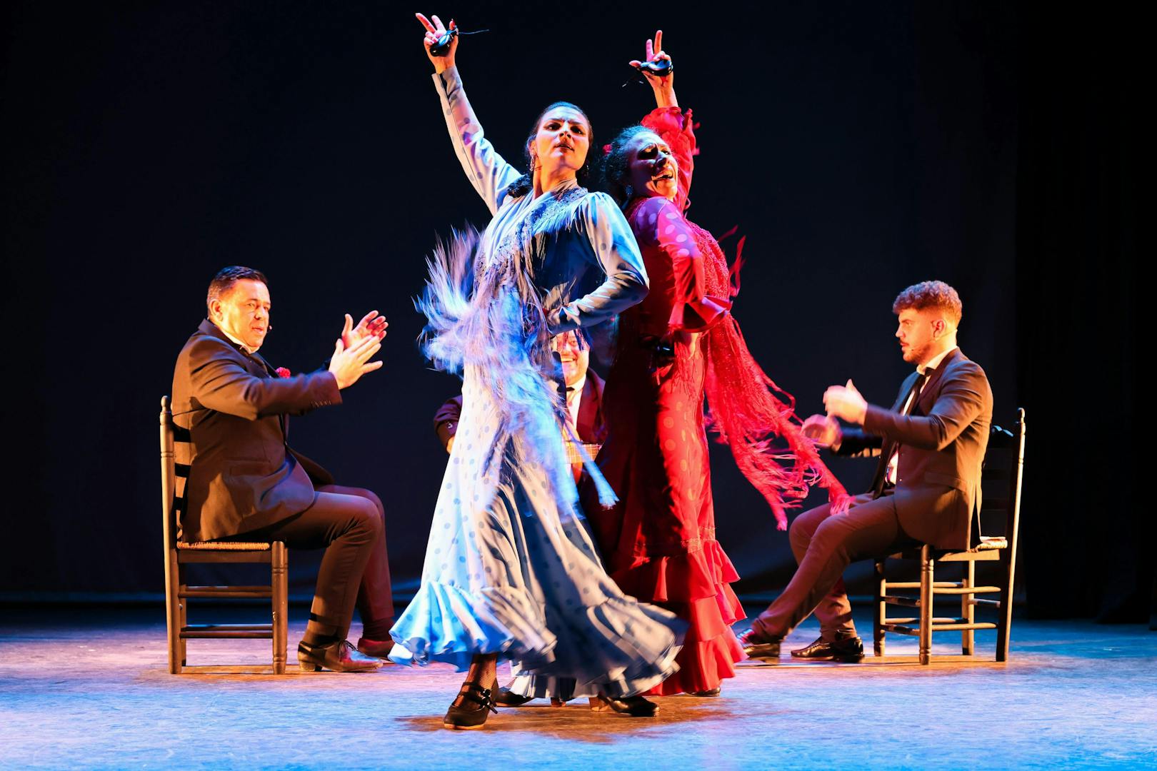 Flamenco dancers performing at Teatro Flamenco Sevilla with musicians clapping.