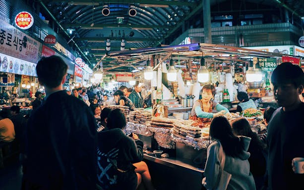 Seoul street food market bustling with people enjoying local dishes.