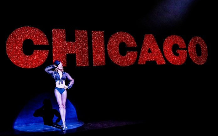 Performer on stage with large red "Chicago" sign in background.