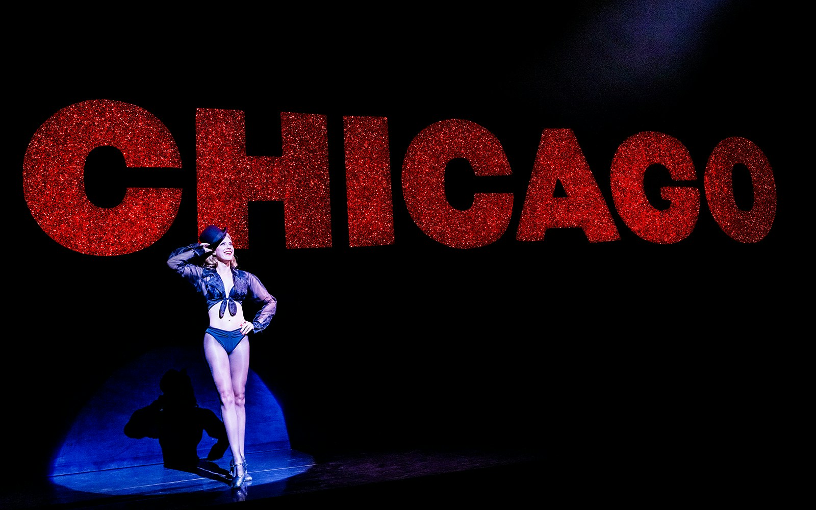 Performer on stage with large red "Chicago" sign in background.