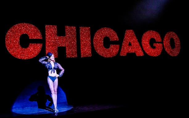 Performer on stage with large red "Chicago" sign in background.