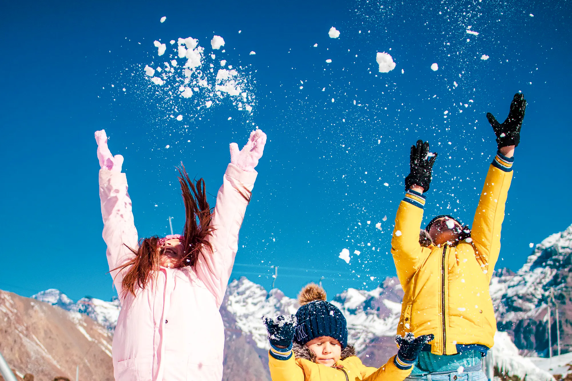 Children playing in snow at El Colorado Ski Resort, Santiago, with mountains in the background.