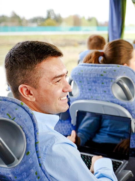Group of passengers smiling and chatting on a travel bus.
