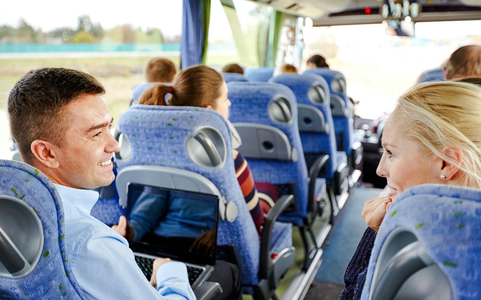 Group of happy passengers in a travel bus with views of the Grand Canyon West Rim.