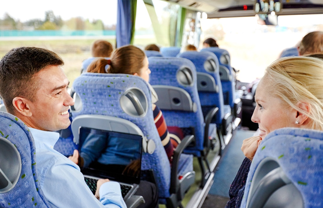 Group of happy passengers in a travel bus with views of the Grand Canyon West Rim.