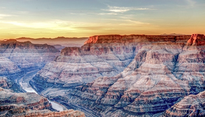 Grand Canyon West Rim at sunset with layered rock formations and river below.
