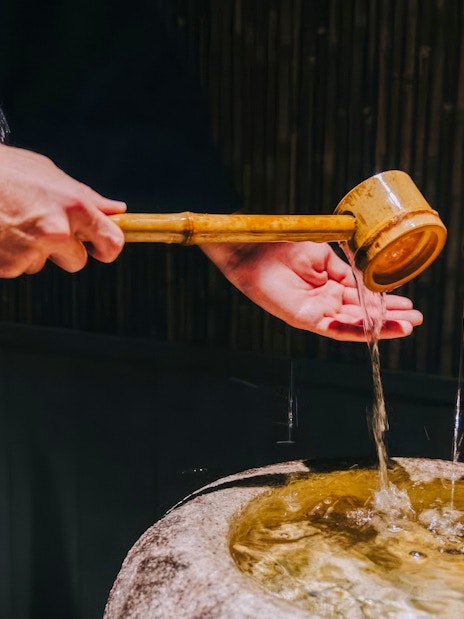 Purifying hands with water from a bamboo ladle before entering the tea room.
