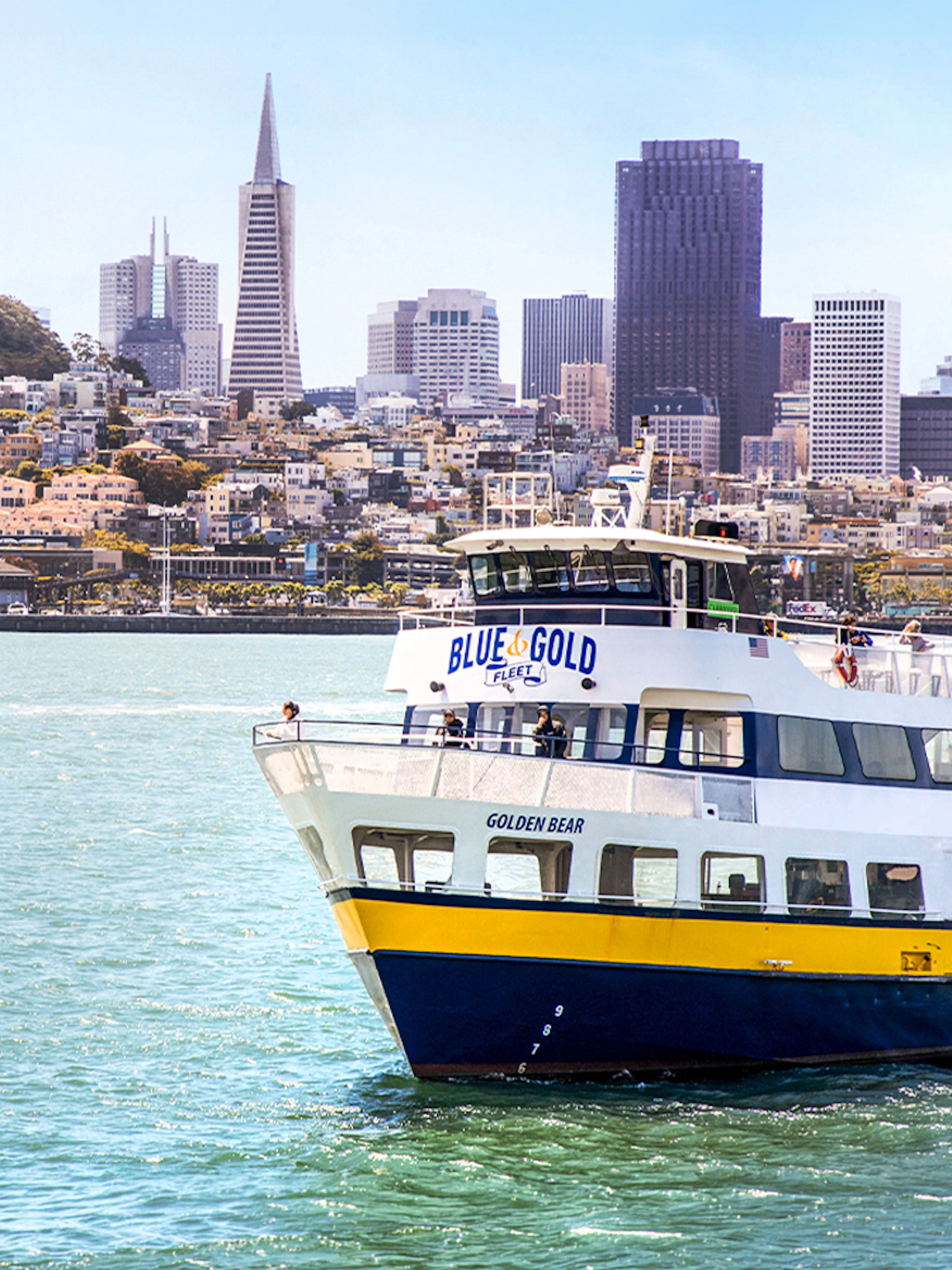 Blue and Gold Fleet ferry cruising in San Francisco Bay with city skyline in the background.