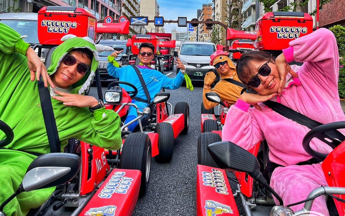 Go-kart riders in costumes on Shibuya streets during guided tour in Tokyo.