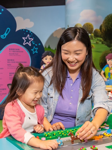 Child and adult building with LEGO bricks at Legoland Hong Kong.