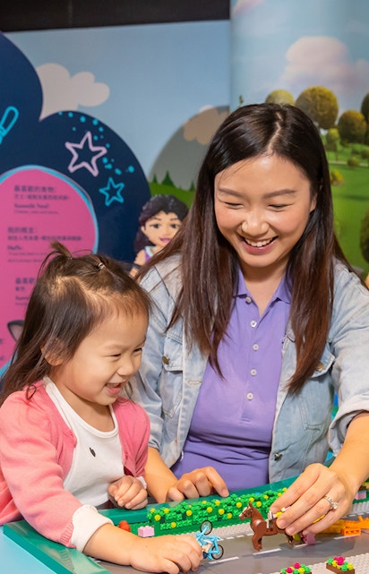 Child and adult building with LEGO bricks at Legoland Hong Kong.