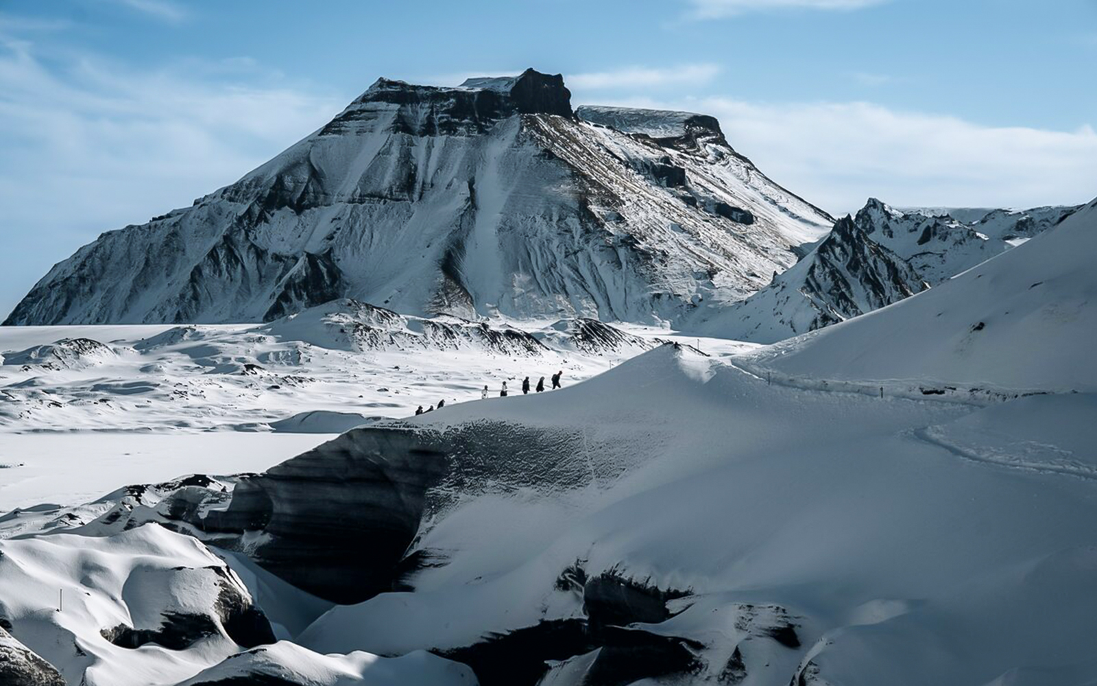 Hikers traversing snowy terrain near Katla Volcano, Iceland.