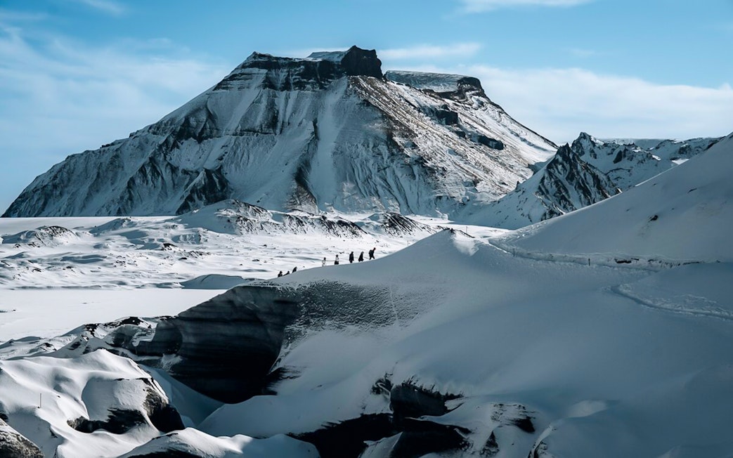 Hikers traversing snowy terrain near Katla Volcano, Iceland.