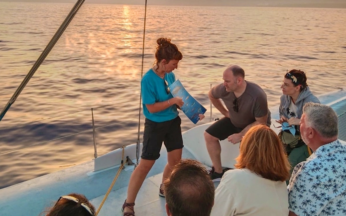 Tourists on a cruise boat in Lanzarote listening to a guide about whale and dolphin watching.