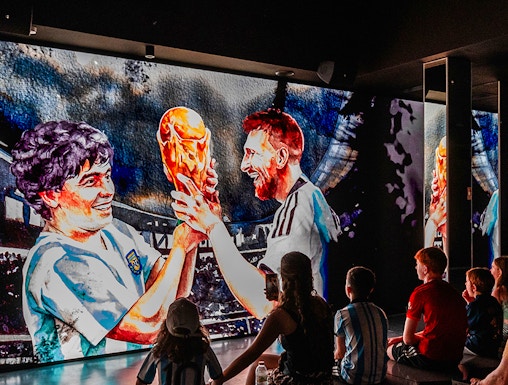 Visitors watching a football legends mural at Legends: The Home of Football Museum.