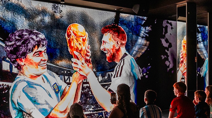 Visitors watching a football legends mural at Legends: The Home of Football Museum.