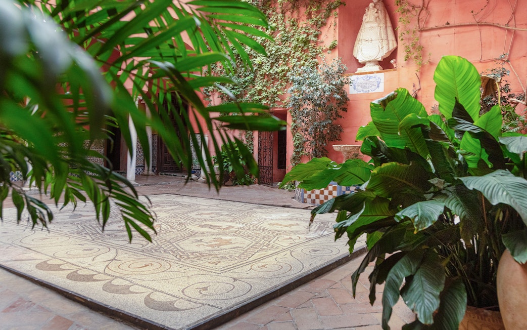 Courtyard with mosaic floor and lush plants at Casa de Salinas, Seville.
