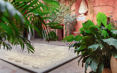Courtyard with mosaic floor and lush plants at Casa de Salinas, Seville.