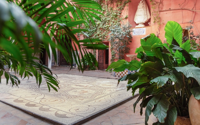 Courtyard with mosaic floor and lush plants at Casa de Salinas, Seville.