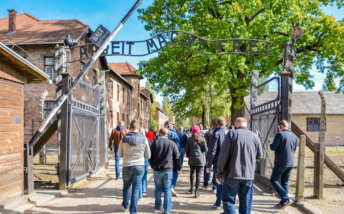 Visitors entering Auschwitz concentration camp under the "Arbeit Macht Frei" sign.