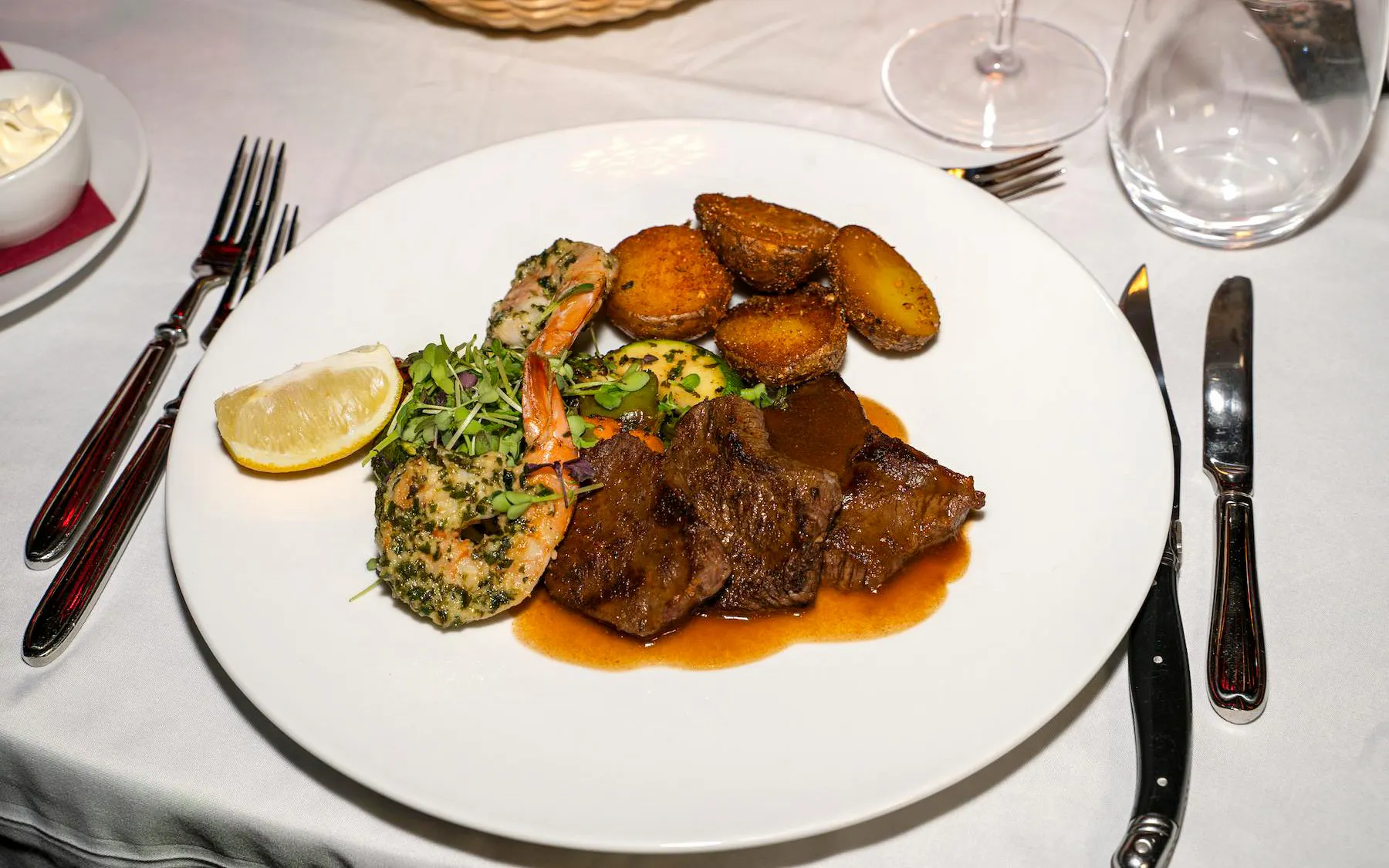 Dinner plate with steak, shrimp, potatoes, and greens at The Mirage dinner show, Vienna.
