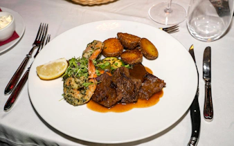 Dinner plate with steak, shrimp, potatoes, and greens at The Mirage dinner show, Vienna.