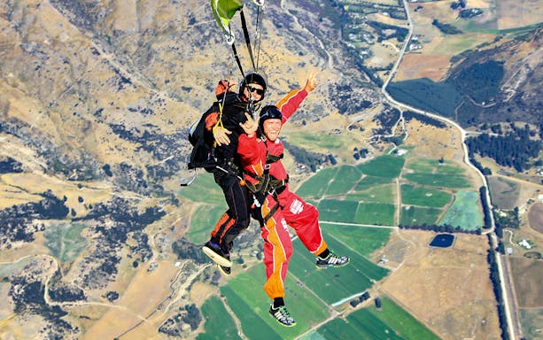 Tandem skydive over Wanaka landscape with fields and hills below.