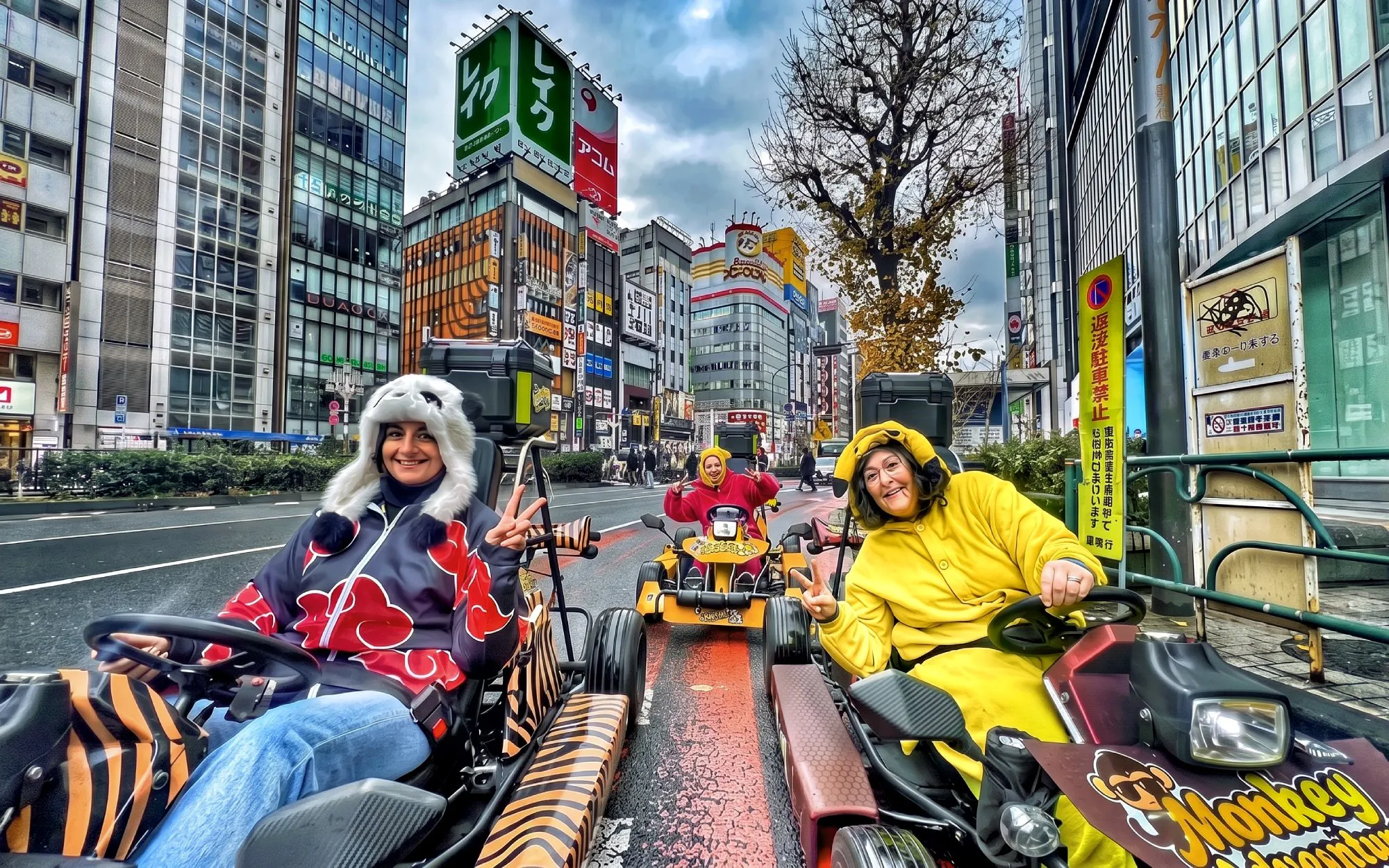 Go-kart riders in costumes driving through Shibuya, Tokyo with cityscape backdrop.