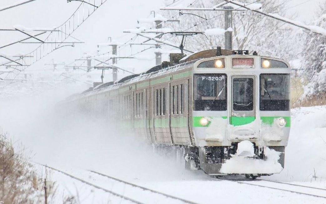 Train traveling through snowy landscape in Hokkaido, Japan, using Hokkaido Rail Pass.
