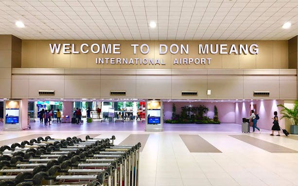Don Mueang Airport entrance with travelers, related to Pattaya private airport transfer and SIM card service.