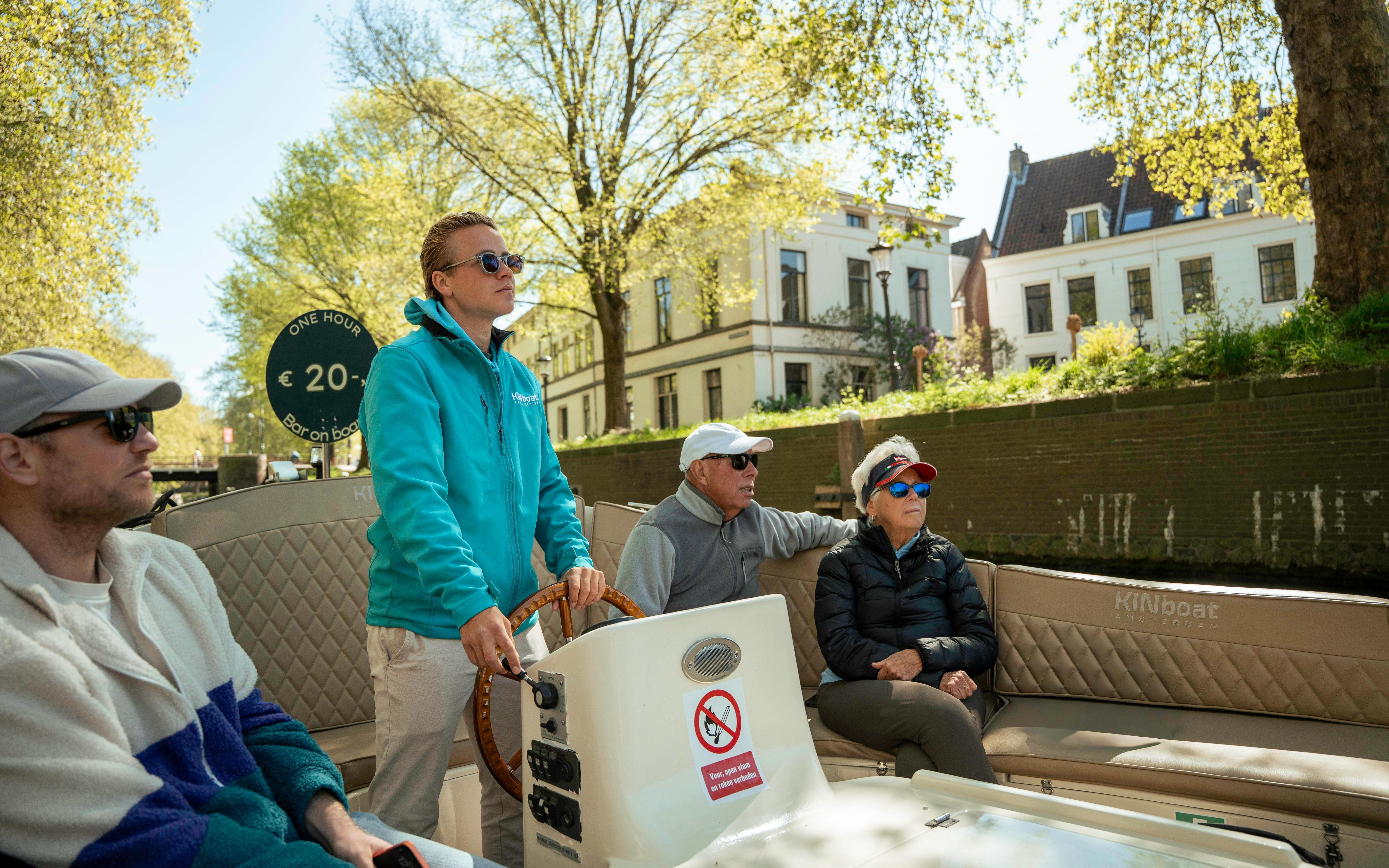 Open boat canal cruise in Utrecht with passengers enjoying the view.