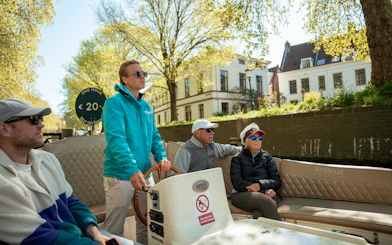 Open boat canal cruise in Utrecht with passengers enjoying the view.